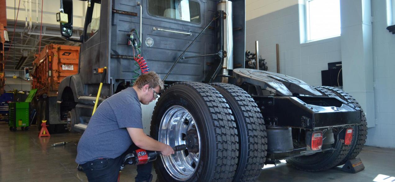 Image of a student using air tools on a truck wheel