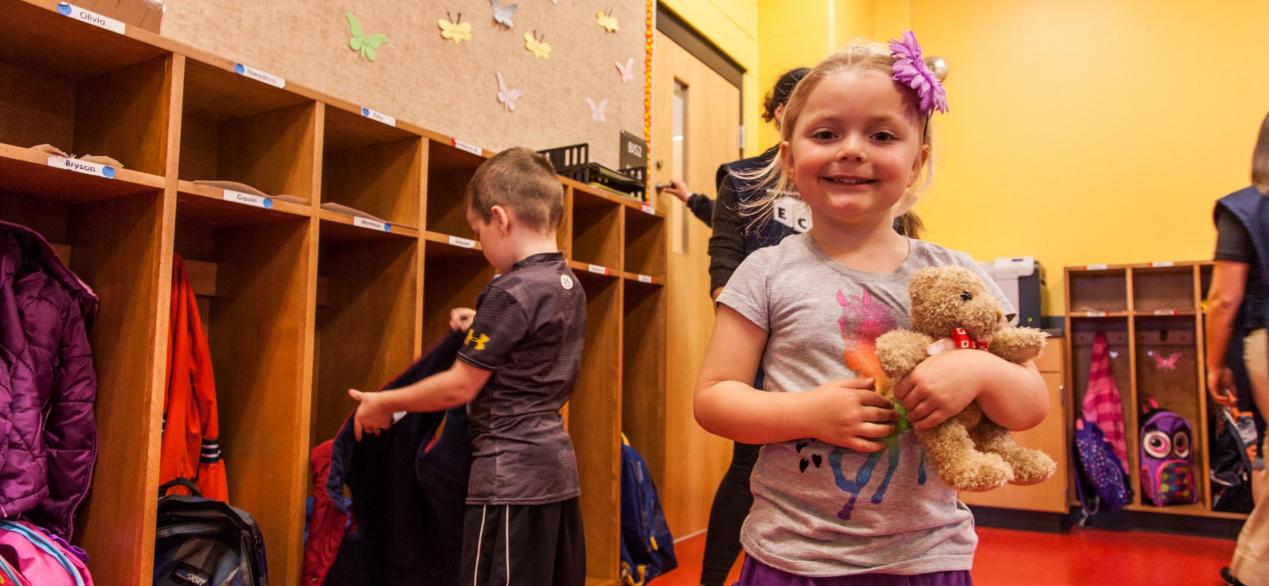 Image of preschooler smiling by lockers