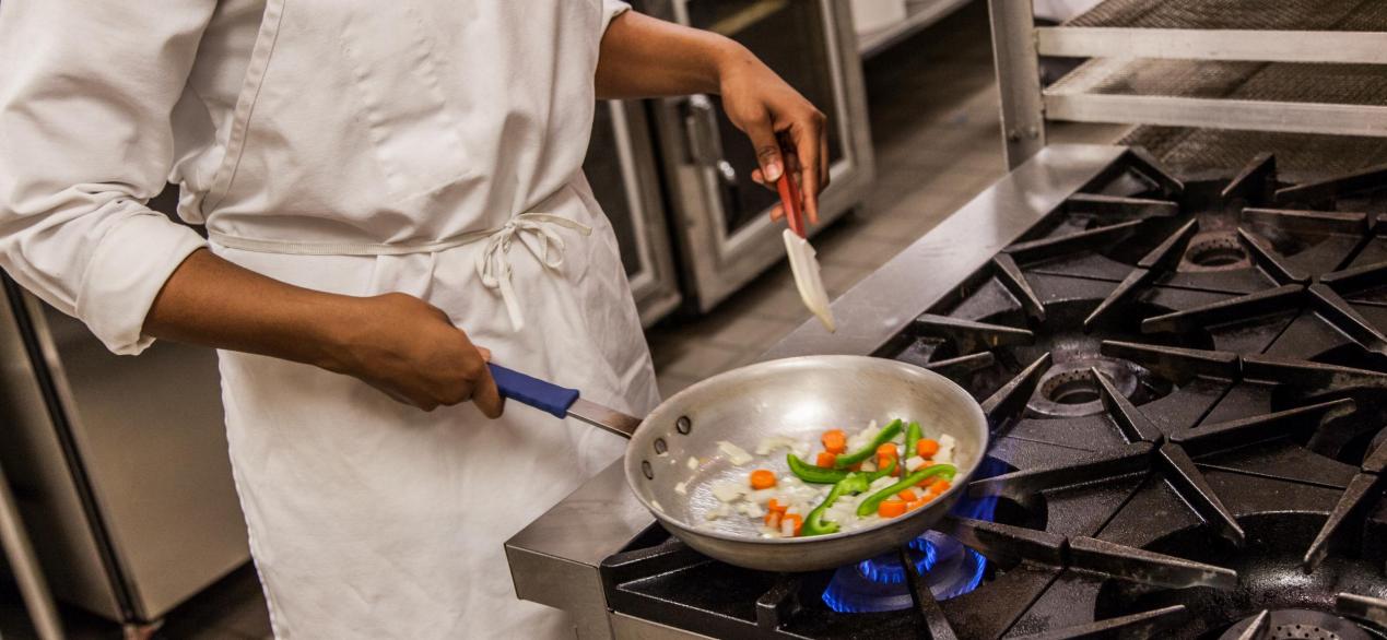 Image of student sauteing veggies on a stove