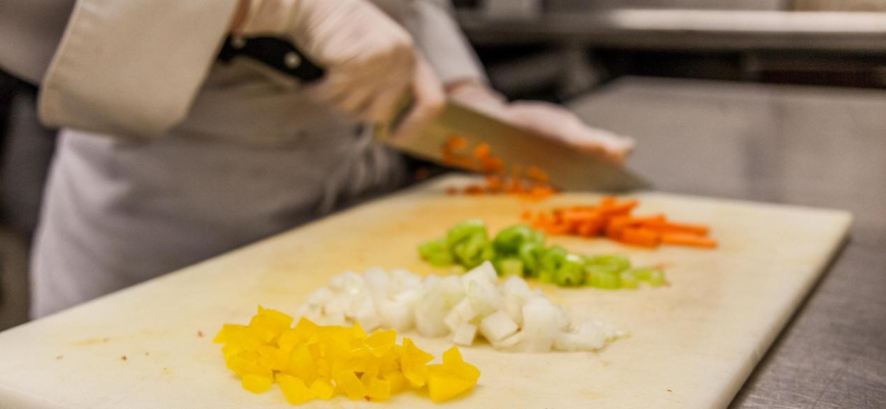 Image of cutting board with student cutting colorful fresh veggies