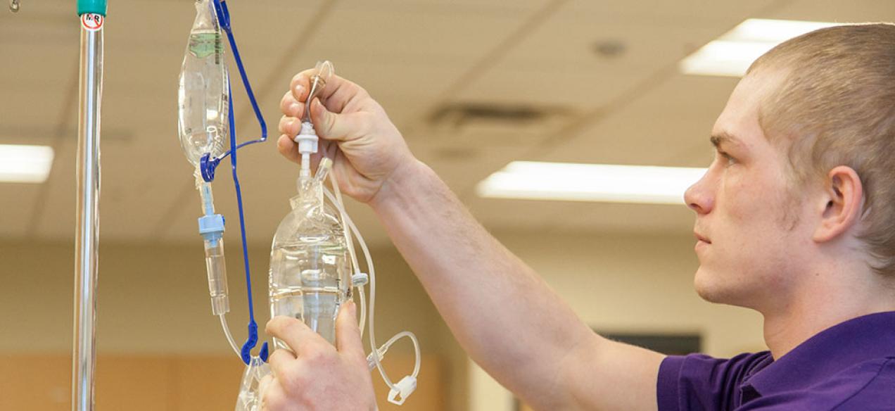 Image of male student hanging an IV bag