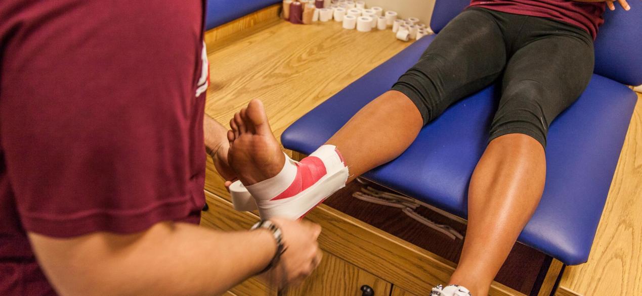 Image of students taping an injured leg 