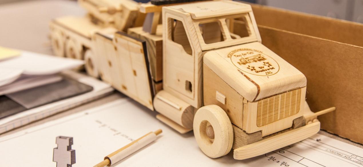 Image of a truck made out of individual wood parts designed by students, CAD drawings underneath truck 
