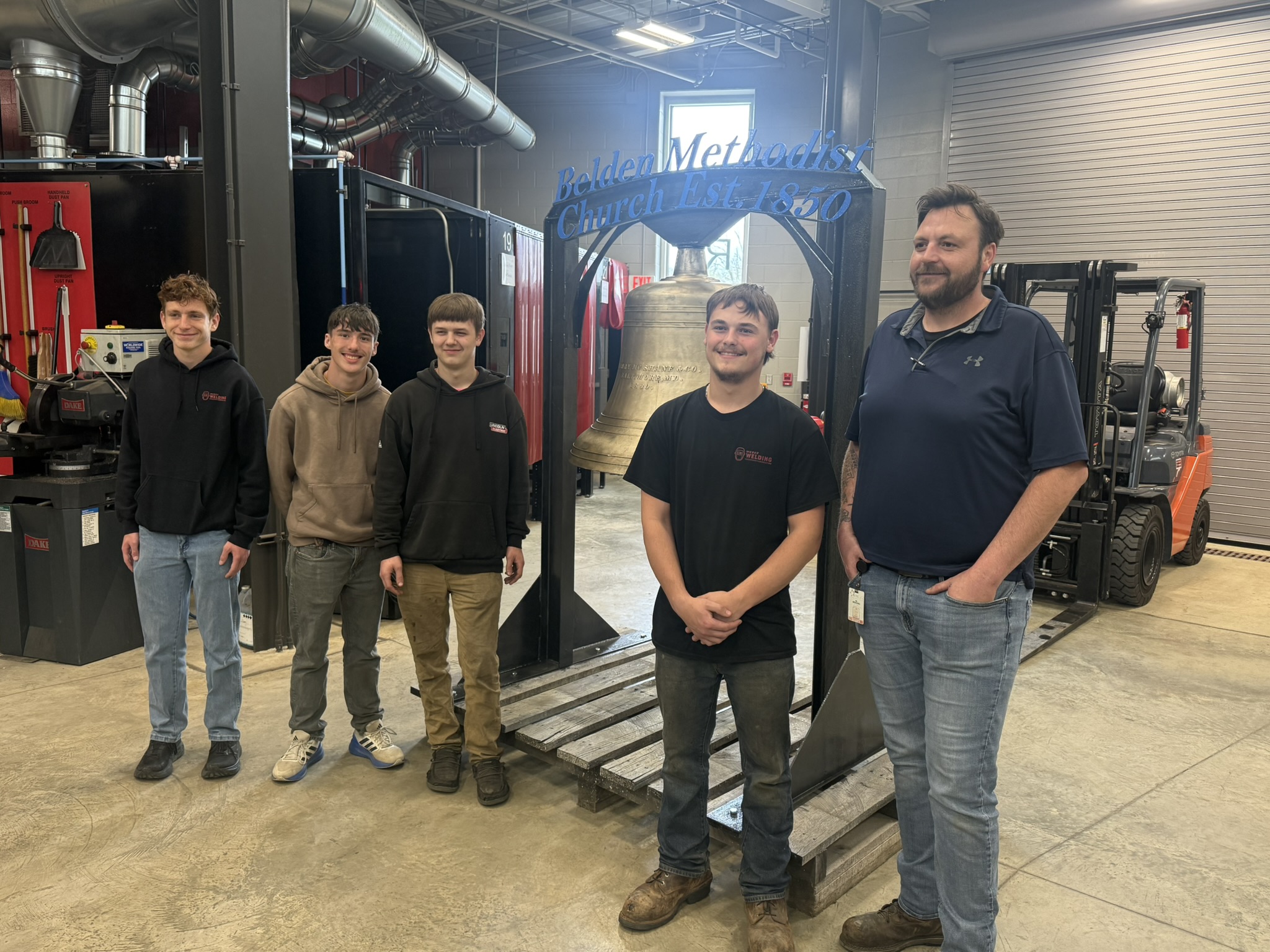 Welding students and teacher pose with the stand they fabricated to support a 600 lb. church bell