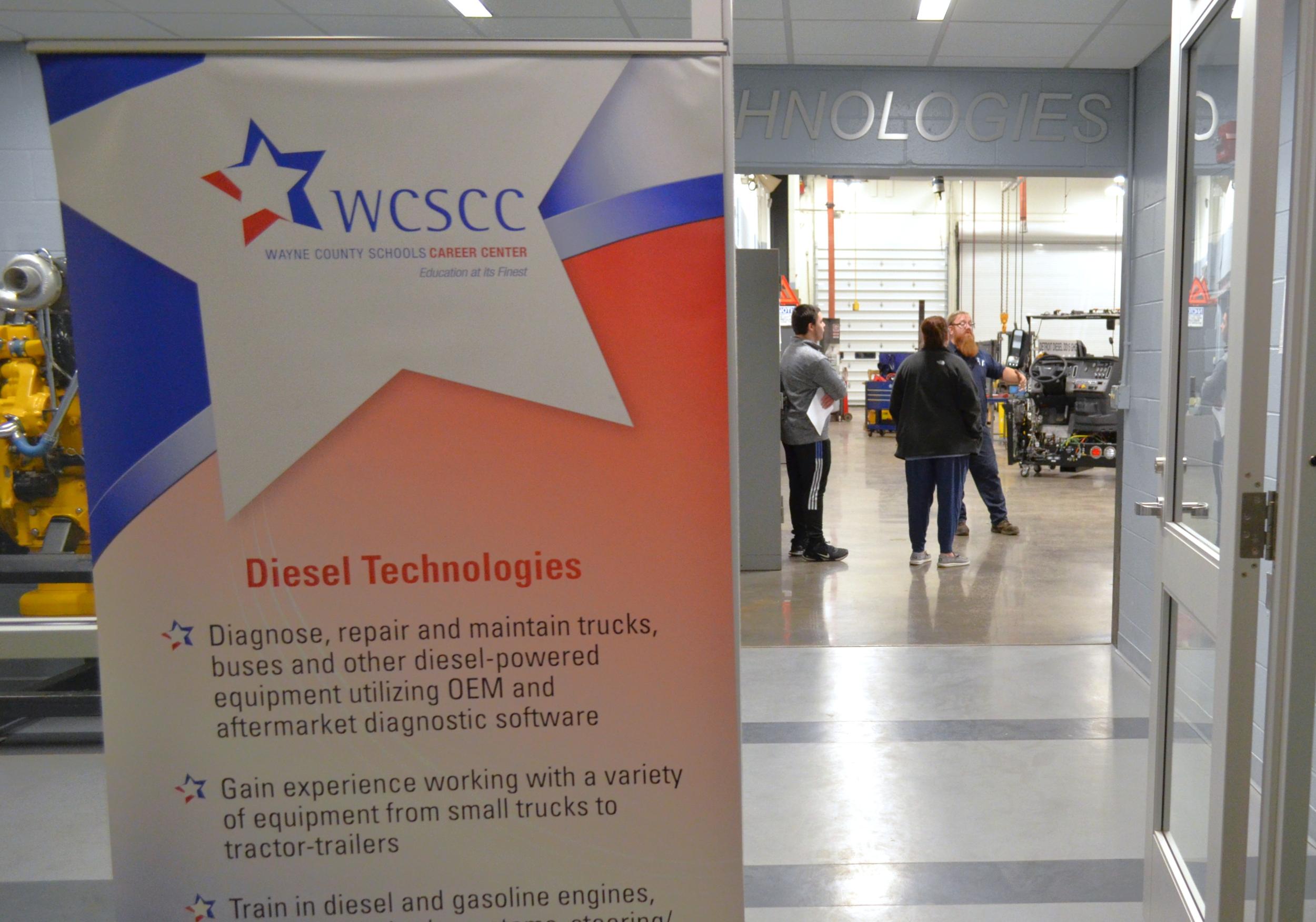 Teacher talks to student and parent at a previous Open House event