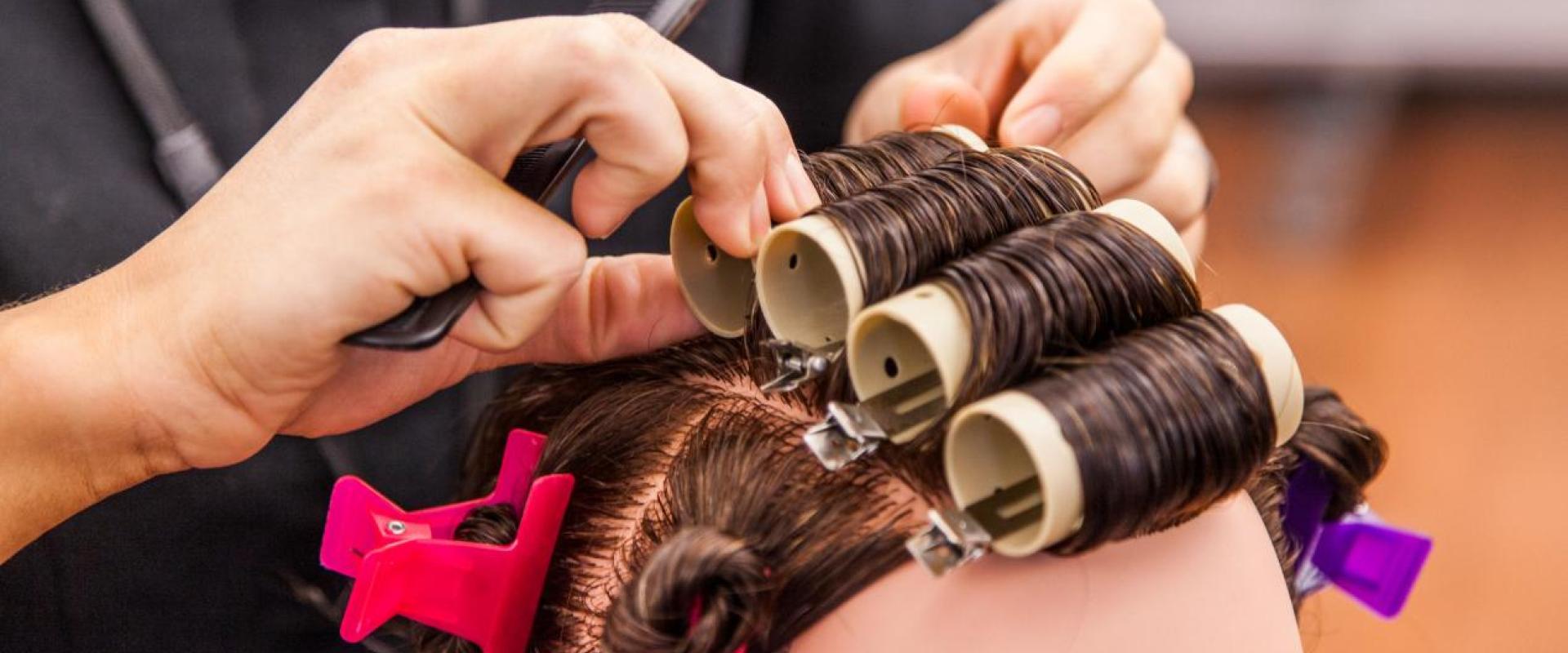 Student putting rollers in a mannequin's hair