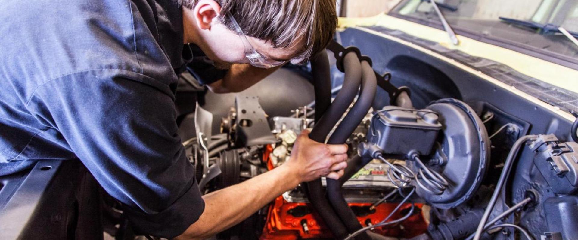 A mechanic working in the engine bay of a vehicle