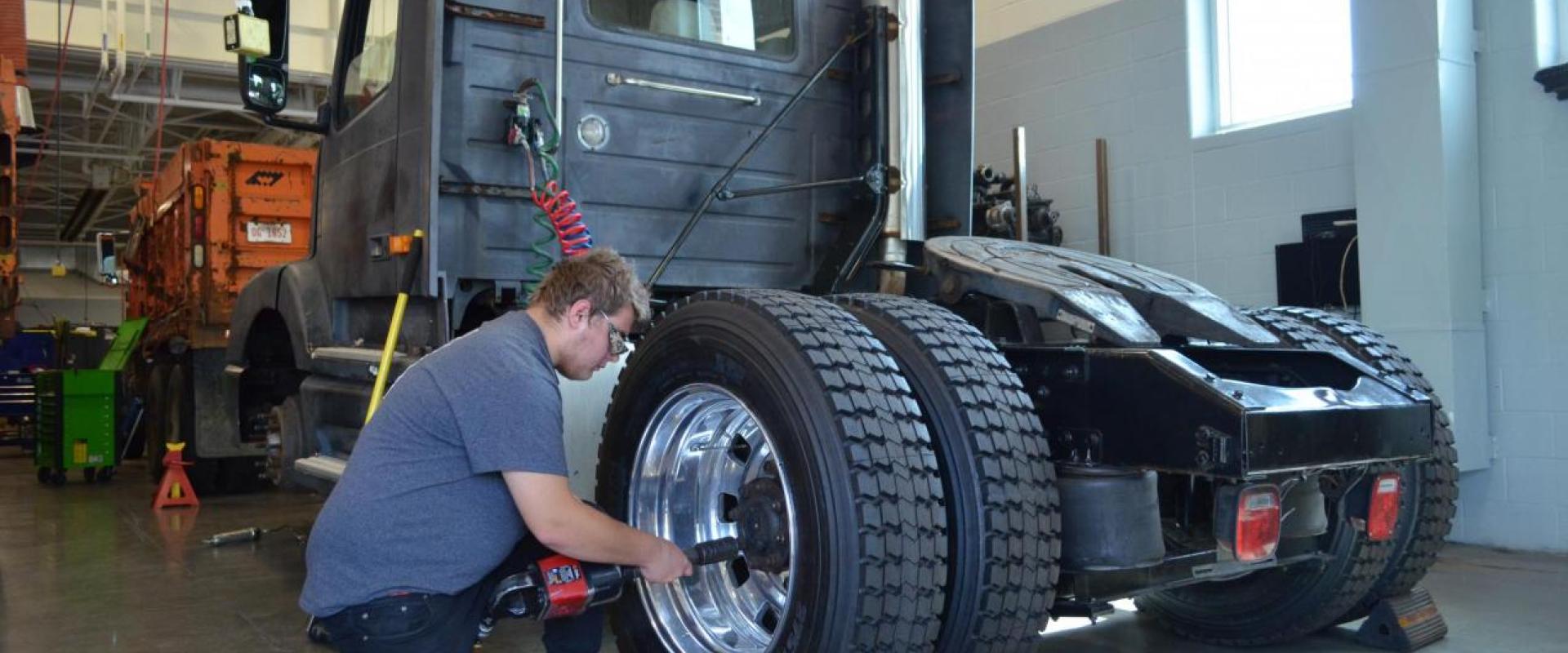 A mechanic working on a tire of a semi-truck