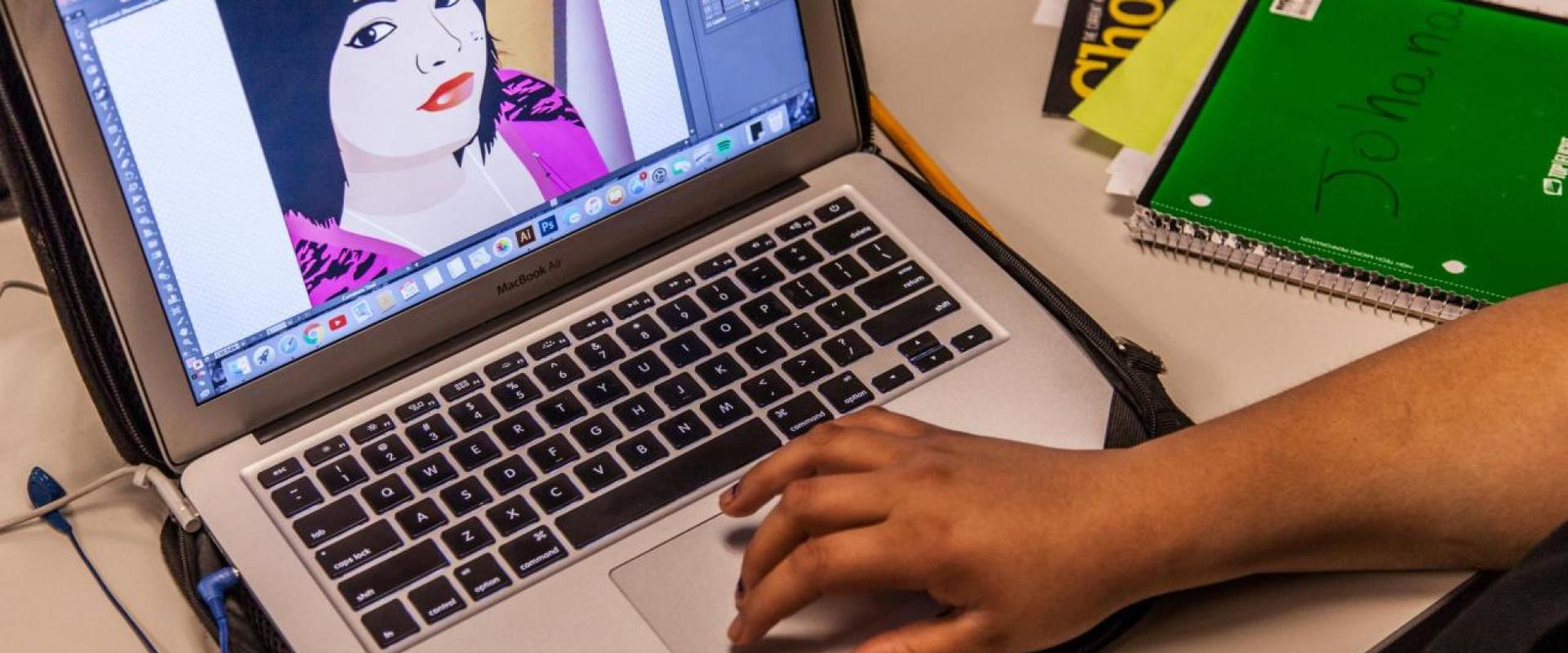 Individual at a computer designing a portrait of a female using graphic design software