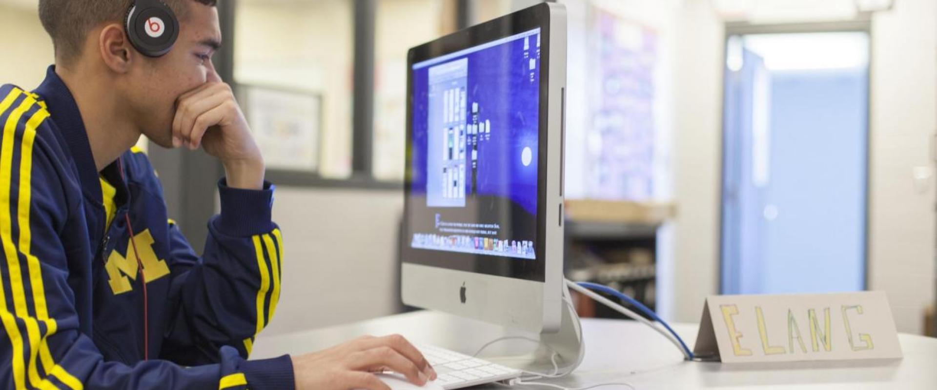 A student at a computer while wearing headphones