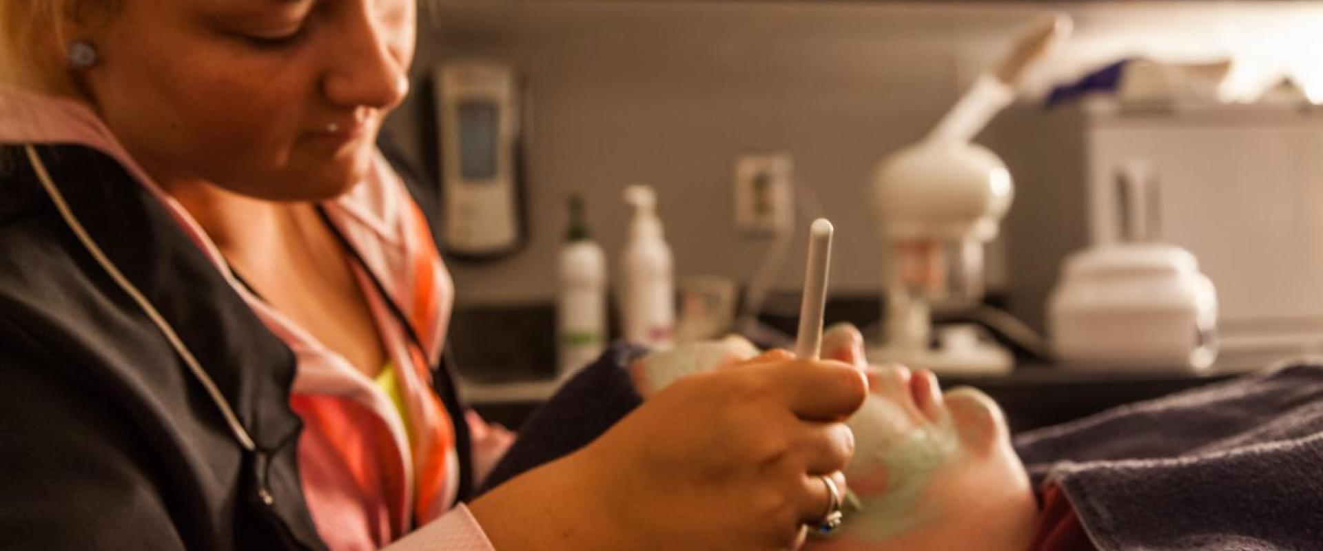 An person using a tool to give another person a facial.  