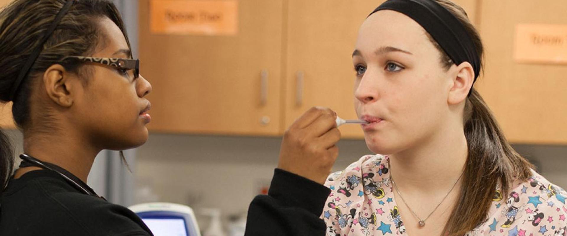 A nurse taking oral temperature of another person