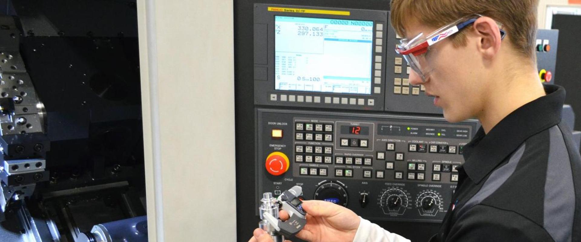 Student measuring a piece milled on a CNC machine