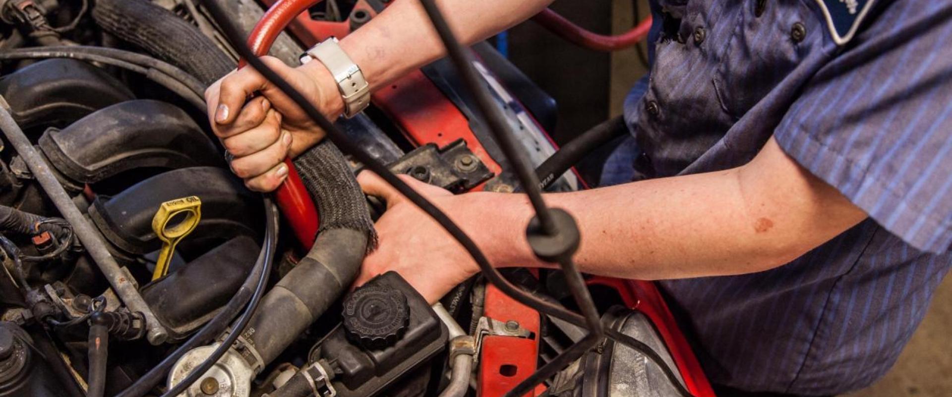 An individual working on an engine of a vehicle