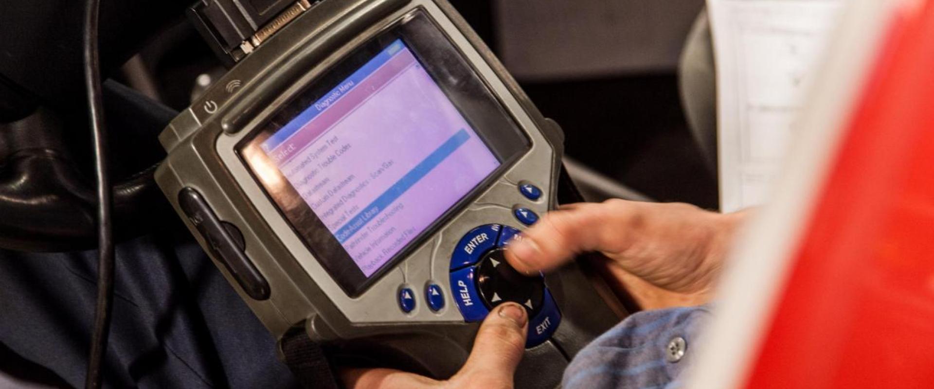 An individual using a OBD-II tool to check an engines codes