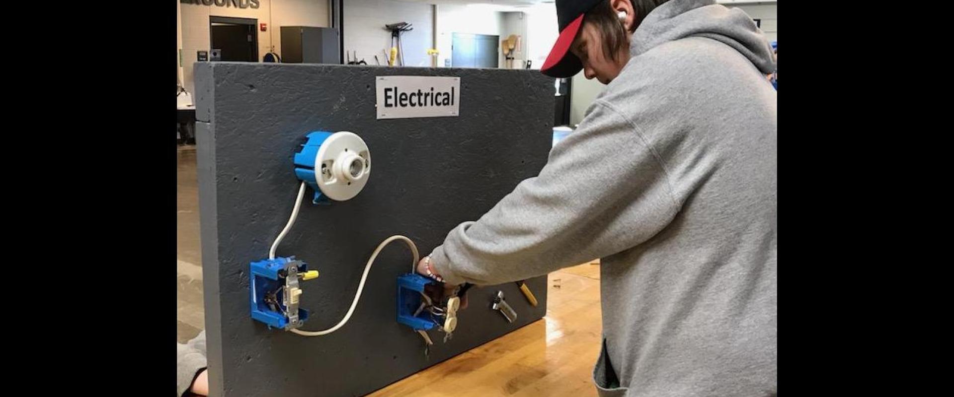 An individual working on a electrical diagram fixed on a board.