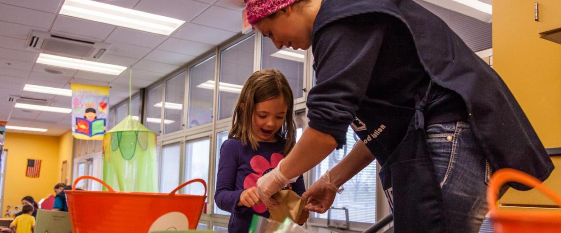 A daycare teacher assisting a young girl with an activity
