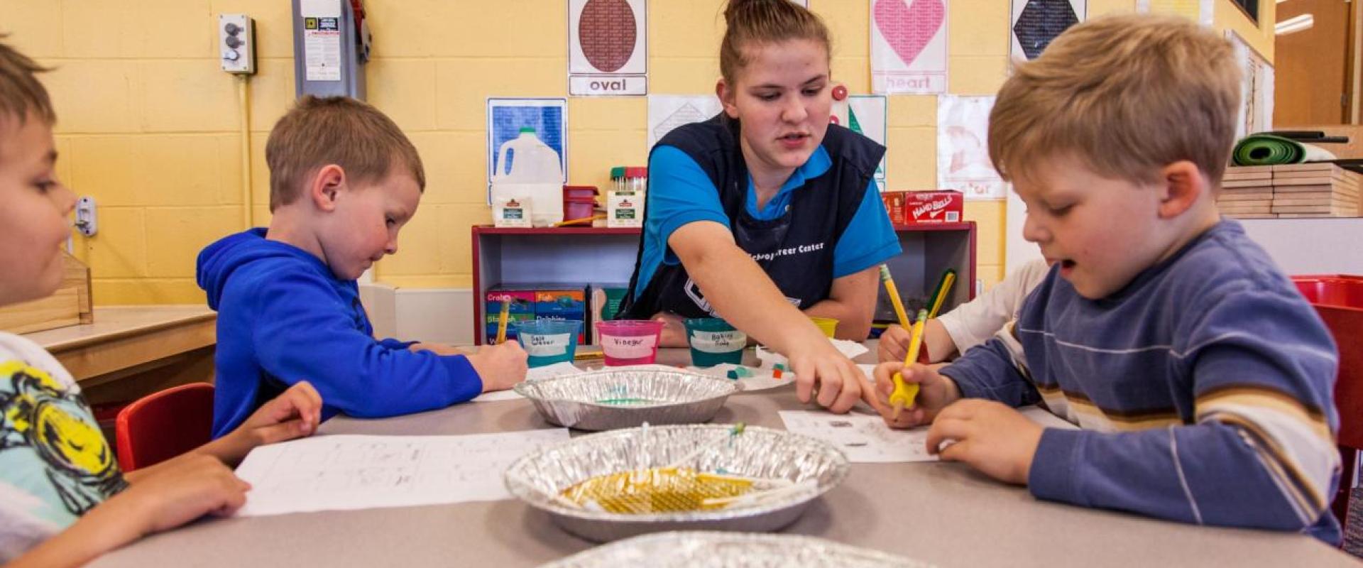 A daycare teacher assisting a group of children with an activity