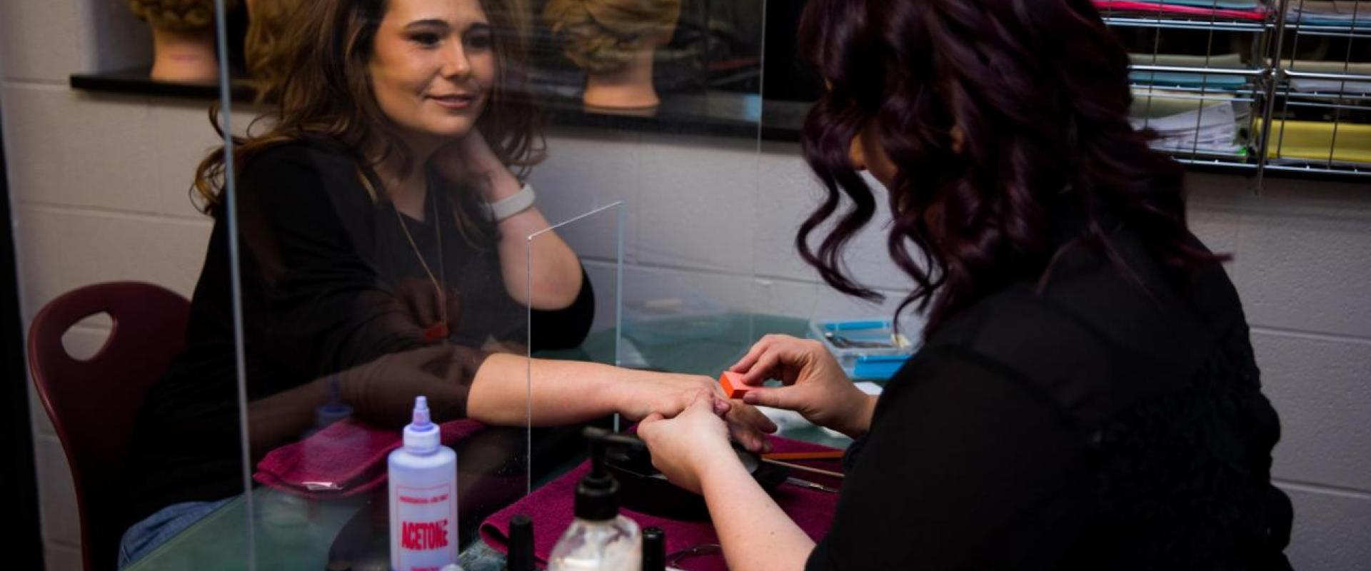 A woman doing another woman's manicure. 