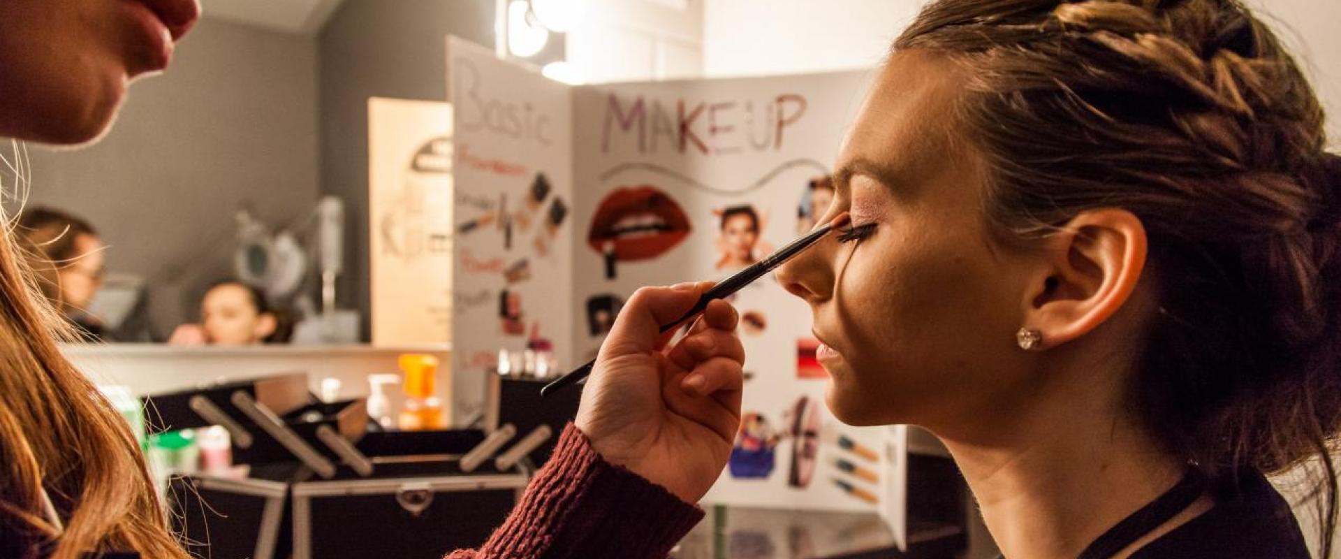 Student applying makeup to another student