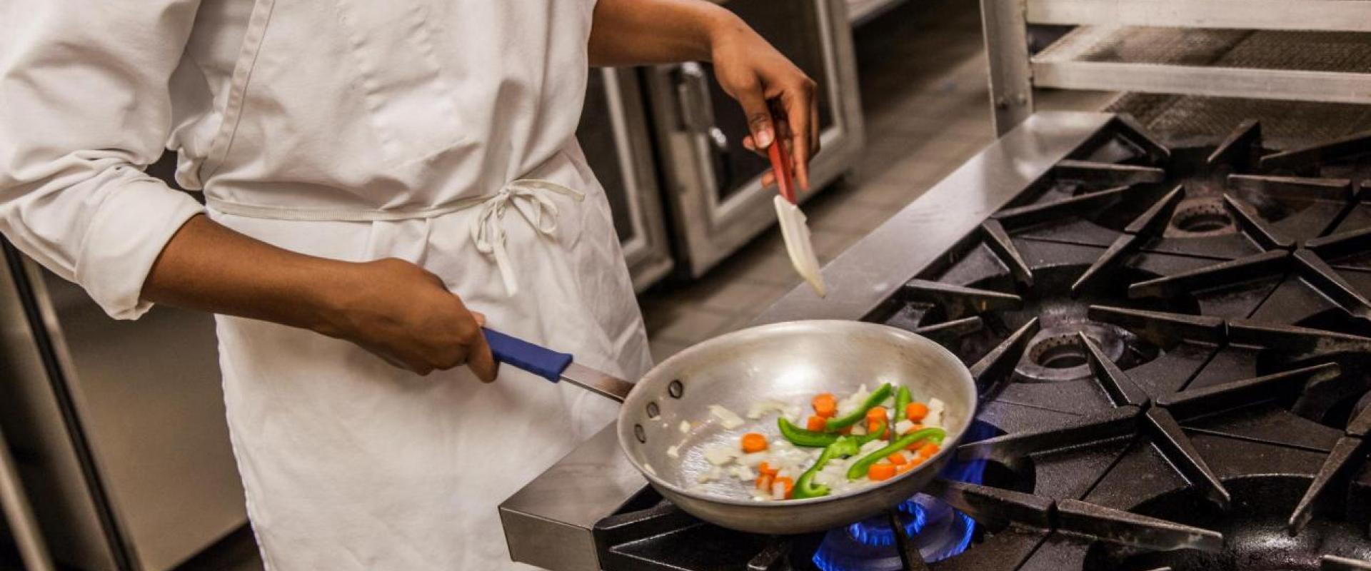 A student sautéing carrots, onions, and carrots