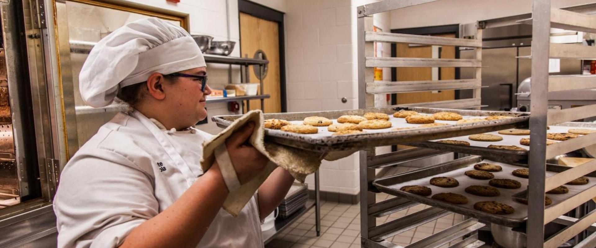 A student loading a rake of cookies