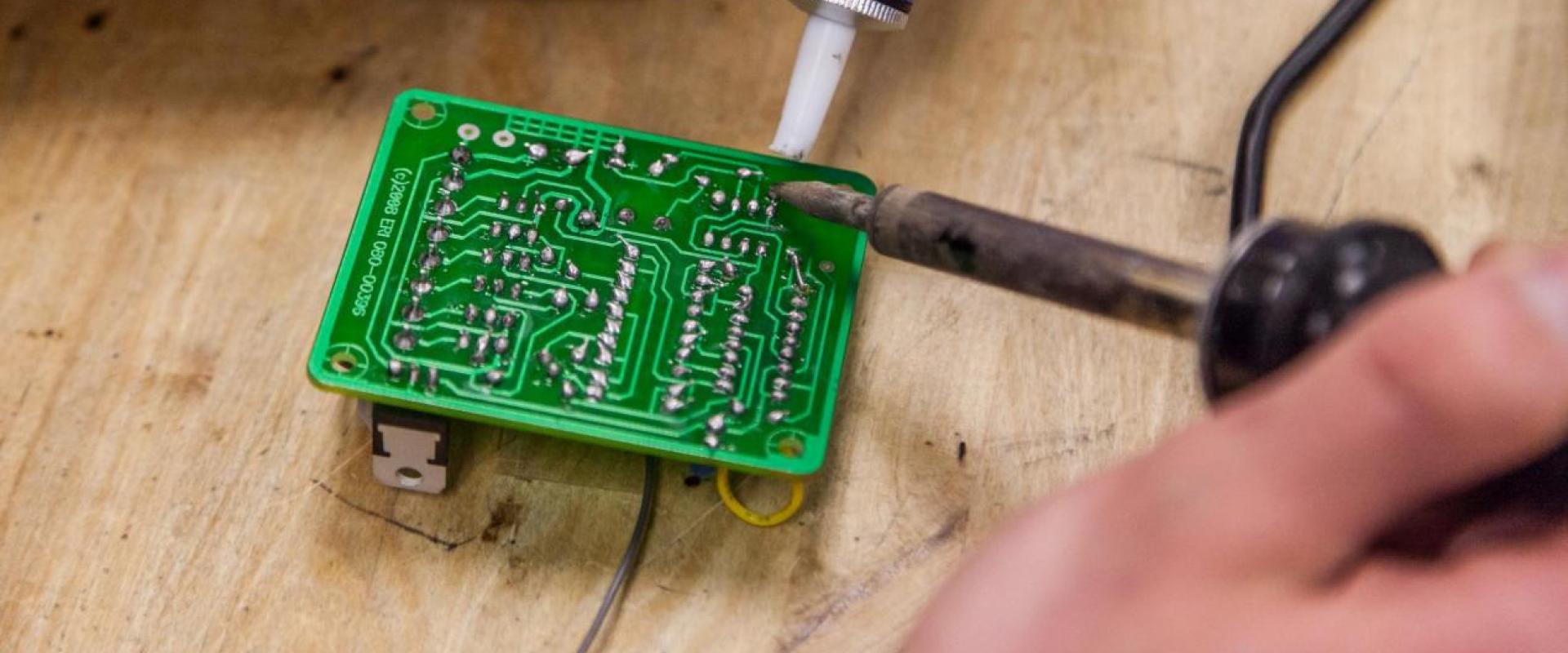 Hands soldering on a microchip