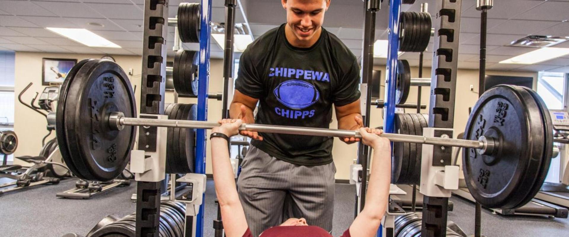 A male spotting another individual on a bench press