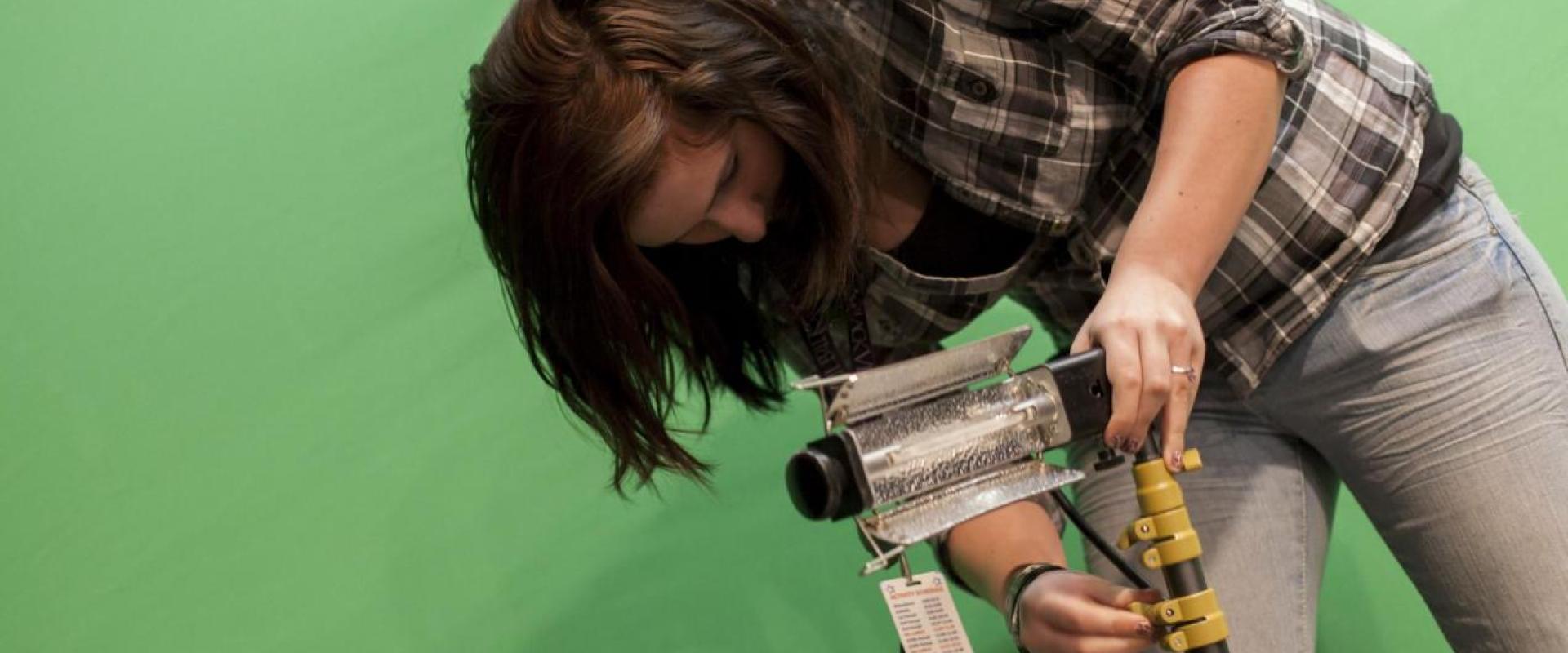 A female setting up a studio light