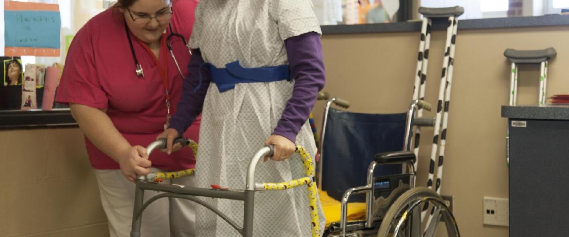 A nurse assisting an individual to stand from wheelchair to a walker