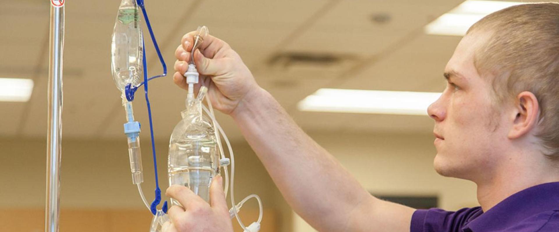 A male adjusting a IV fluid bag