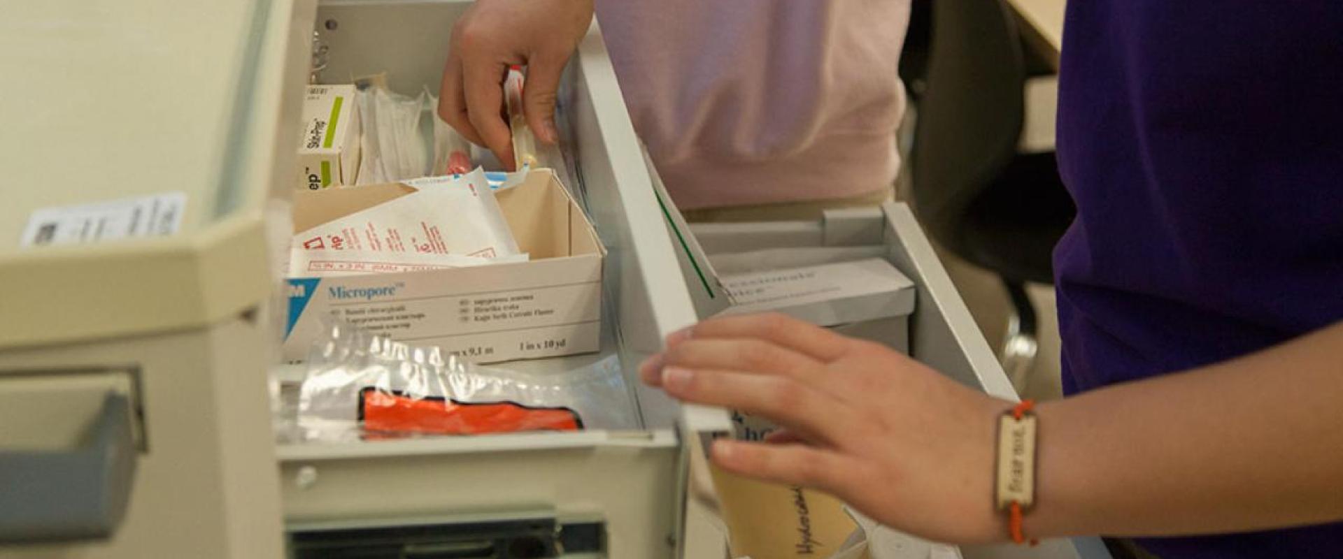An individual grabbing an item out of a nurses cart