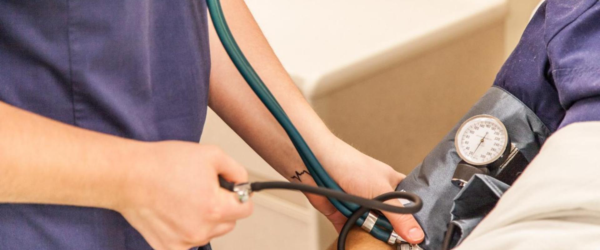 Someone taking blood-pressure of a patient