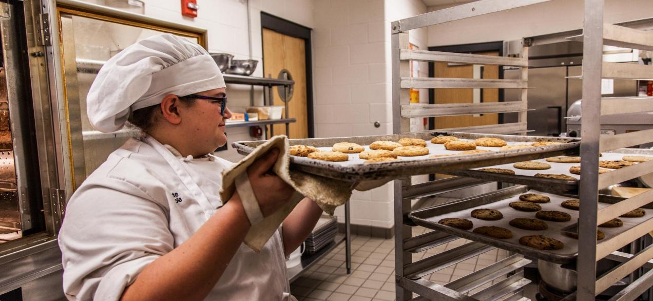 Image of student making cookies on large cookie sheets