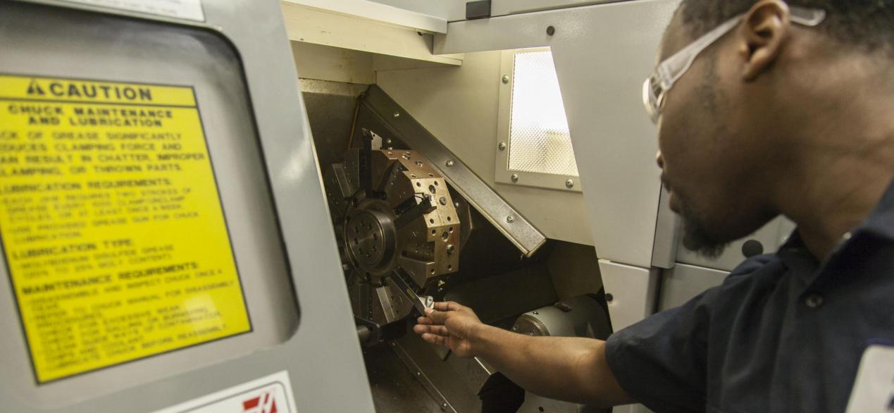 Image student getting a part out of a CNC machine 