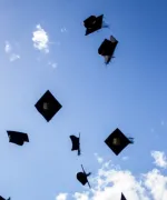 Graduation caps being thrown in the air. 